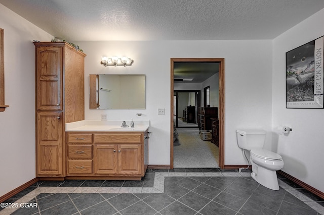 bathroom featuring vanity, tile patterned flooring, a textured ceiling, and toilet