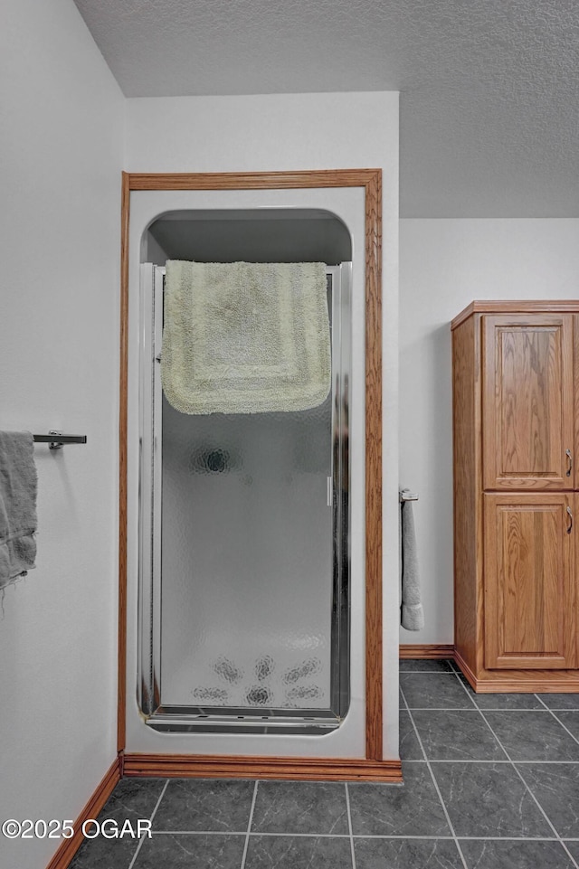 details featuring a shower with door and a textured ceiling