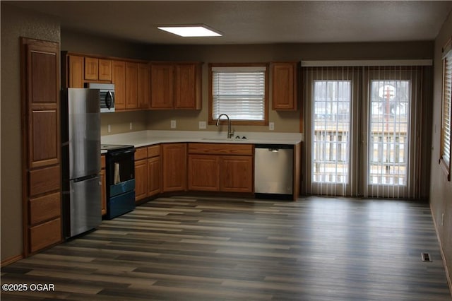 kitchen with a healthy amount of sunlight, appliances with stainless steel finishes, sink, and dark hardwood / wood-style flooring