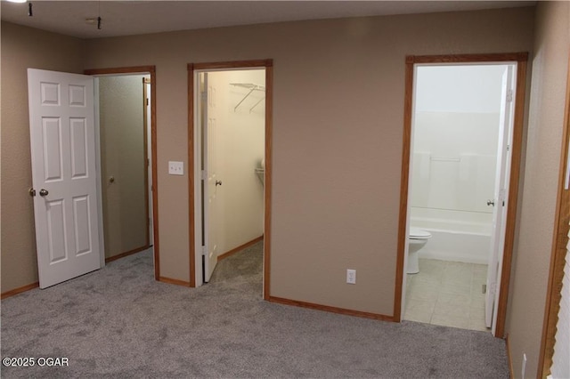 unfurnished bedroom with light colored carpet, ensuite bathroom, a spacious closet, and a closet