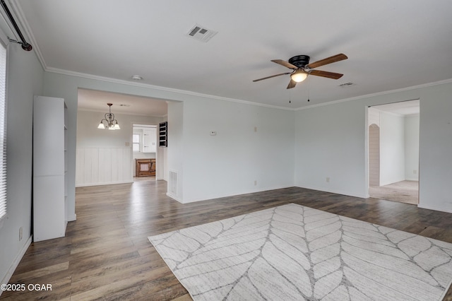 empty room with crown molding, visible vents, wainscoting, wood finished floors, and ceiling fan with notable chandelier