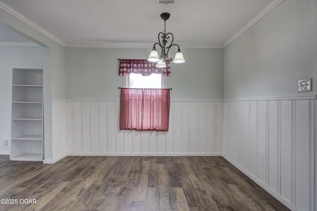 unfurnished dining area with built in shelves, wood finished floors, and wainscoting