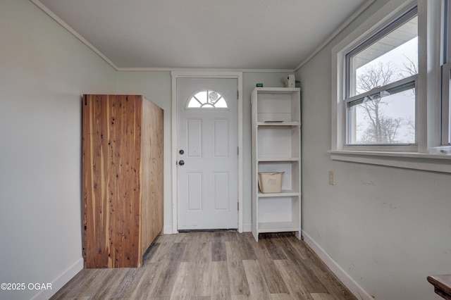 foyer featuring baseboards, wood finished floors, and crown molding