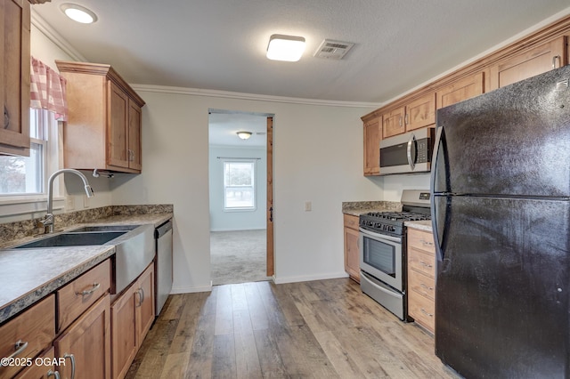 kitchen with appliances with stainless steel finishes, light wood-style flooring, visible vents, and crown molding