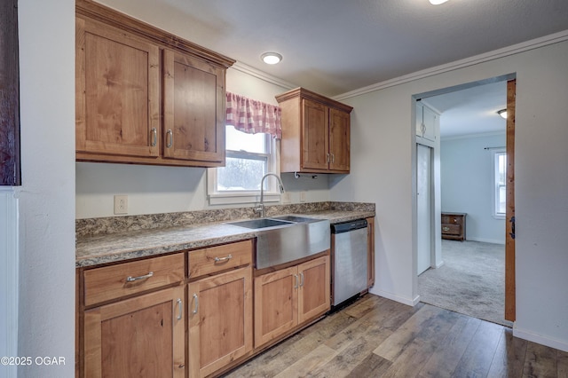 kitchen featuring crown molding, light wood-style flooring, stainless steel dishwasher, a sink, and baseboards