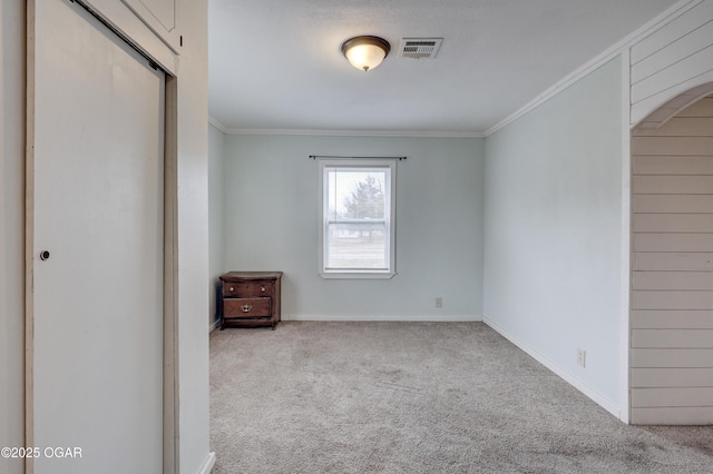 unfurnished bedroom with carpet, arched walkways, crown molding, visible vents, and baseboards