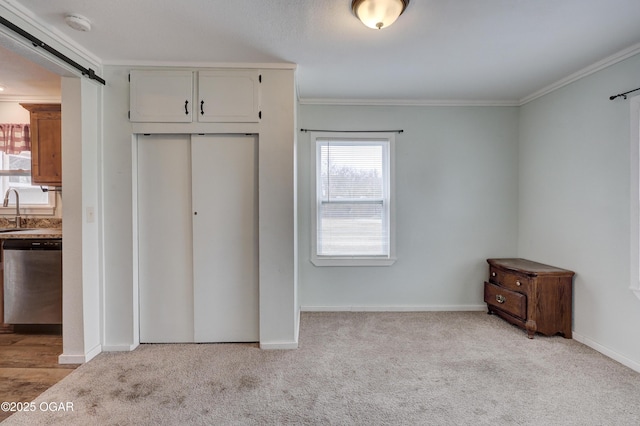 unfurnished bedroom with a barn door, light colored carpet, baseboards, ornamental molding, and a closet