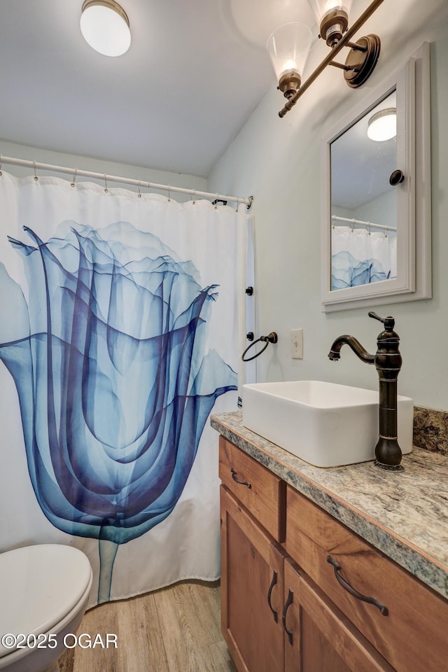 bathroom featuring toilet, shower / tub combo with curtain, wood finished floors, and vanity