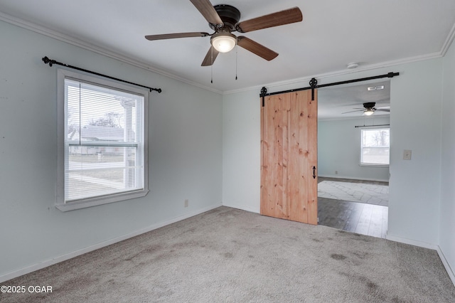 unfurnished room with carpet flooring, crown molding, baseboards, and a barn door