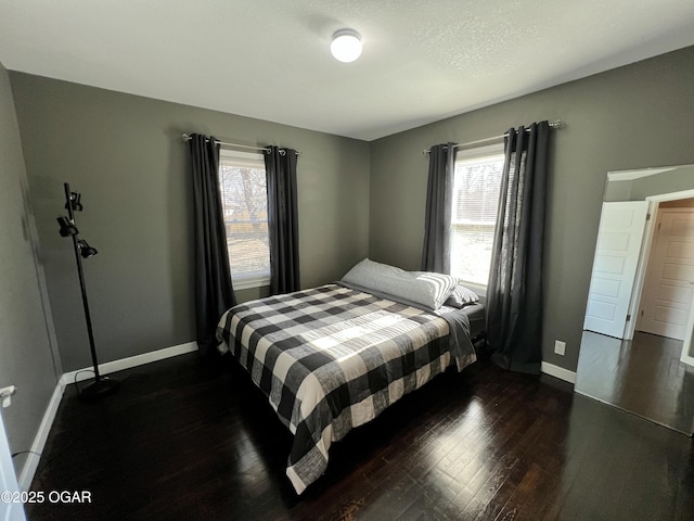 bedroom with multiple windows and dark hardwood / wood-style floors