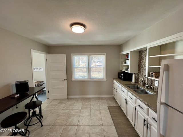 kitchen with white cabinetry, sink, dark stone counters, white fridge, and a textured ceiling