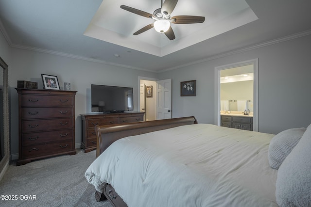 bedroom featuring crown molding, light colored carpet, ensuite bath, and a tray ceiling