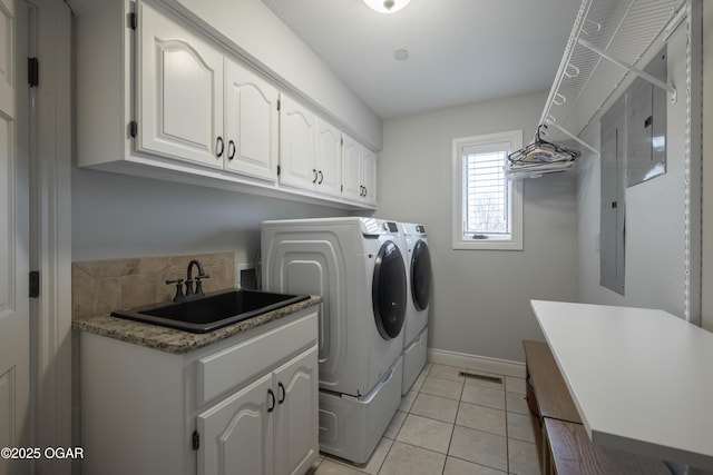 washroom with sink, light tile patterned floors, washer and clothes dryer, and cabinets