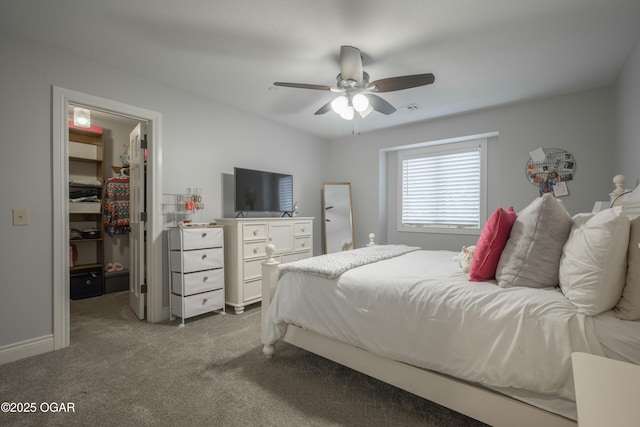 bedroom featuring a walk in closet, a closet, ceiling fan, and carpet