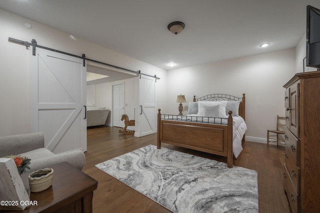 bedroom featuring a barn door and dark hardwood / wood-style floors