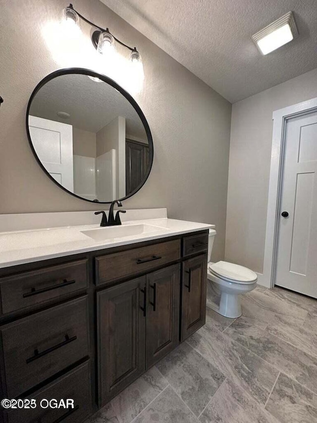 bathroom featuring vanity, a textured ceiling, and toilet