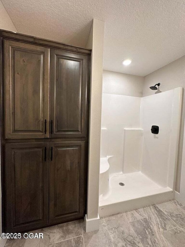 bathroom with a shower and a textured ceiling