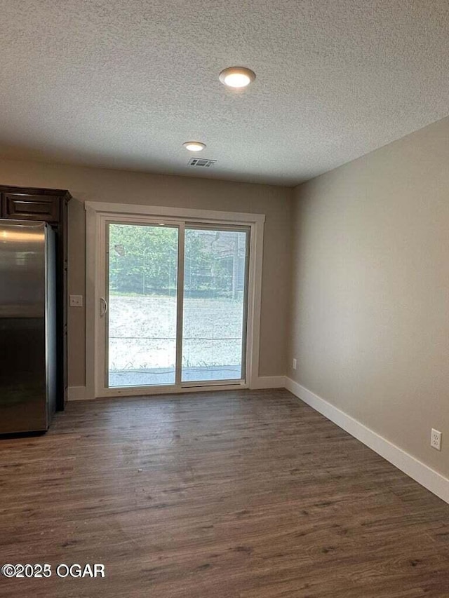 unfurnished room featuring dark wood-type flooring and a textured ceiling