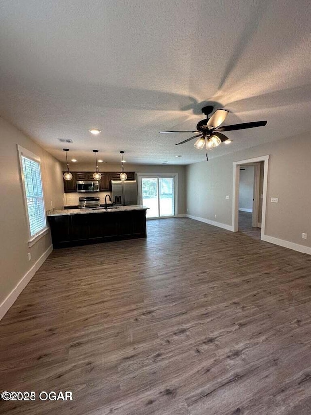 unfurnished living room with dark wood-type flooring, ceiling fan, sink, and a textured ceiling