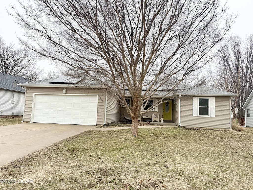 single story home featuring a garage, a front lawn, and solar panels