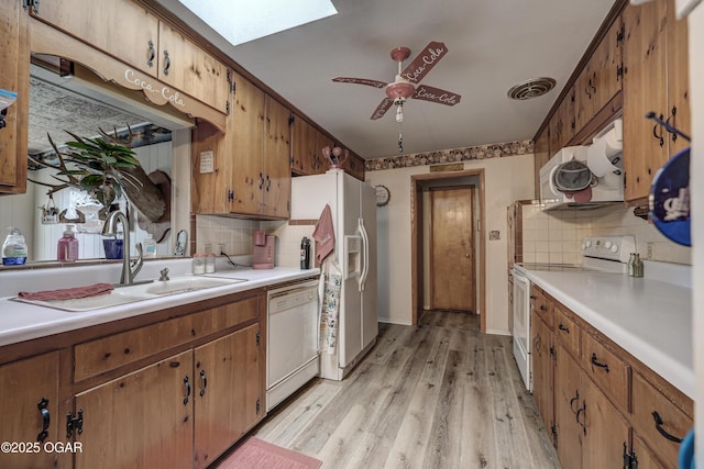 kitchen featuring sink, white appliances, light hardwood / wood-style flooring, ceiling fan, and a skylight