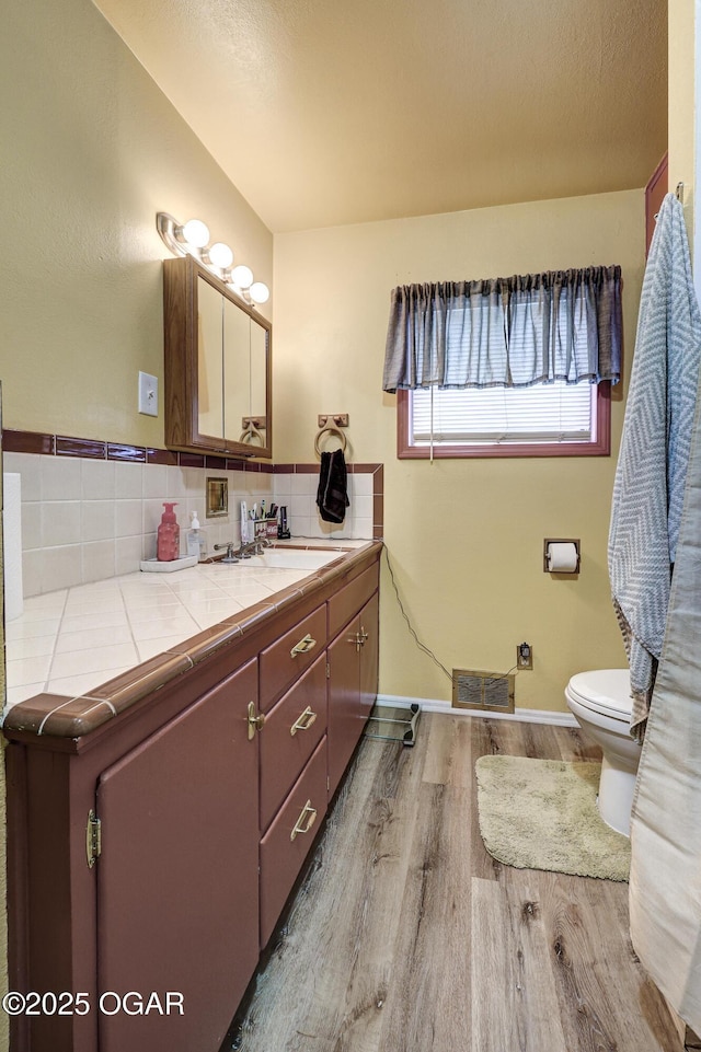 bathroom with hardwood / wood-style flooring, vanity, tasteful backsplash, a textured ceiling, and toilet