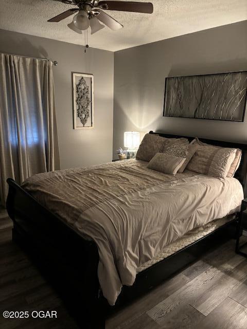 bedroom with ceiling fan, dark hardwood / wood-style floors, and a textured ceiling