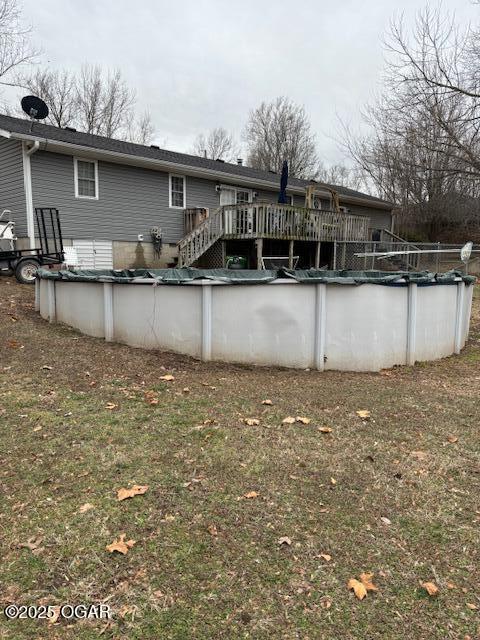 rear view of property featuring a yard and a swimming pool side deck