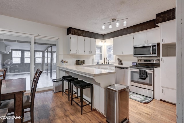 kitchen featuring white cabinetry, appliances with stainless steel finishes, light hardwood / wood-style floors, and sink