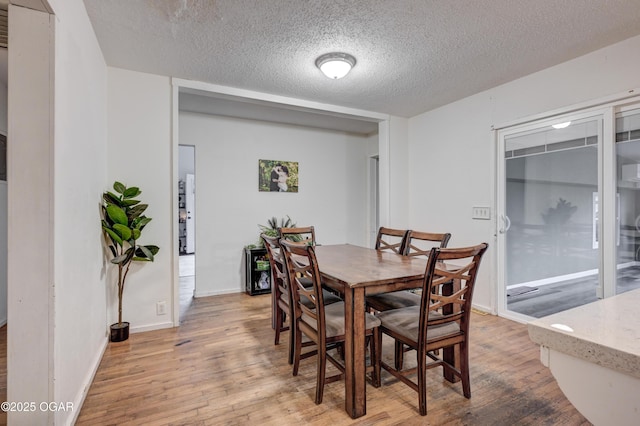 dining area featuring a textured ceiling and light hardwood / wood-style floors