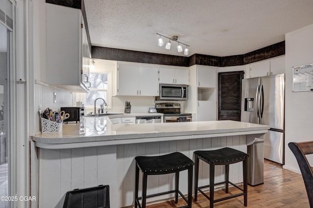 kitchen featuring sink, a textured ceiling, stainless steel appliances, and white cabinets