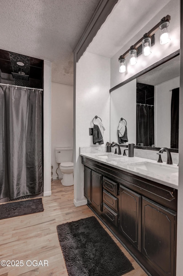 bathroom with hardwood / wood-style flooring, vanity, a textured ceiling, and toilet