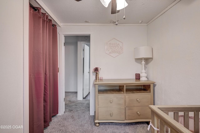 bedroom featuring light carpet, ceiling fan, a crib, and a textured ceiling