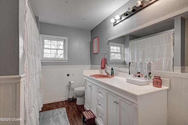 bathroom featuring a healthy amount of sunlight, toilet, wood-type flooring, and a textured ceiling