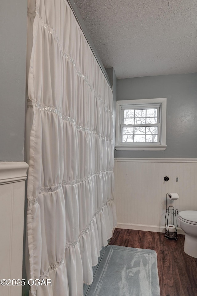 bathroom with toilet, hardwood / wood-style floors, and a textured ceiling