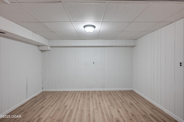 basement with a paneled ceiling and light hardwood / wood-style floors