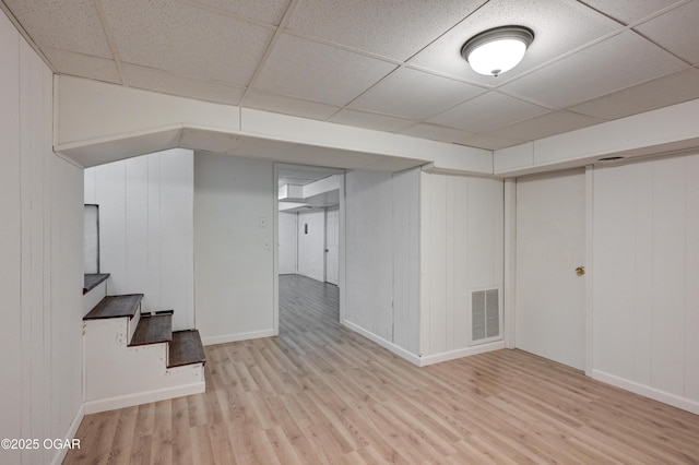 basement with a drop ceiling and light wood-type flooring