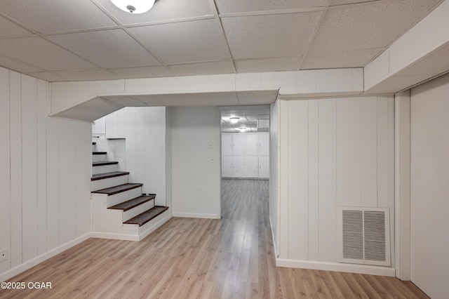 basement with light hardwood / wood-style floors and a drop ceiling