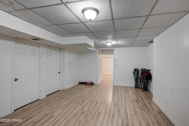 basement featuring a paneled ceiling and light hardwood / wood-style floors