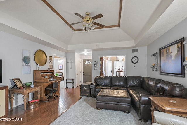 living room with a tray ceiling, wood-type flooring, and ceiling fan