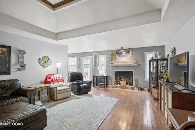 living room with wood-type flooring, a tray ceiling, and a textured ceiling