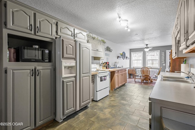 kitchen with ceiling fan, white electric range oven, sink, and a textured ceiling