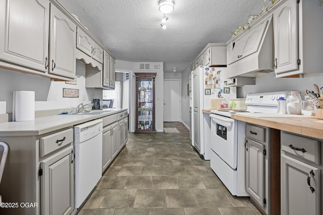 kitchen featuring butcher block counters, sink, gray cabinetry, a textured ceiling, and white appliances