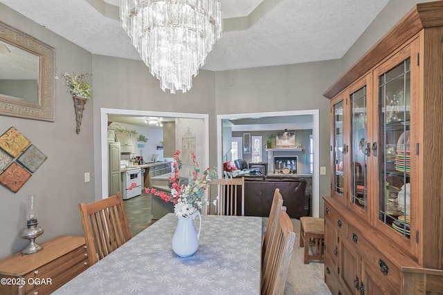 carpeted dining area with a notable chandelier and a textured ceiling