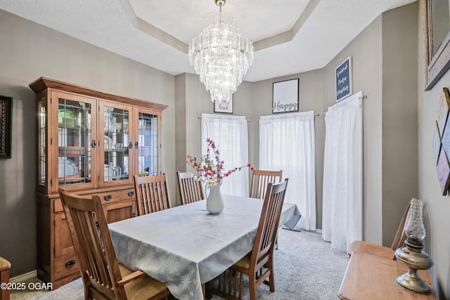 dining room with a raised ceiling, light carpet, and a notable chandelier