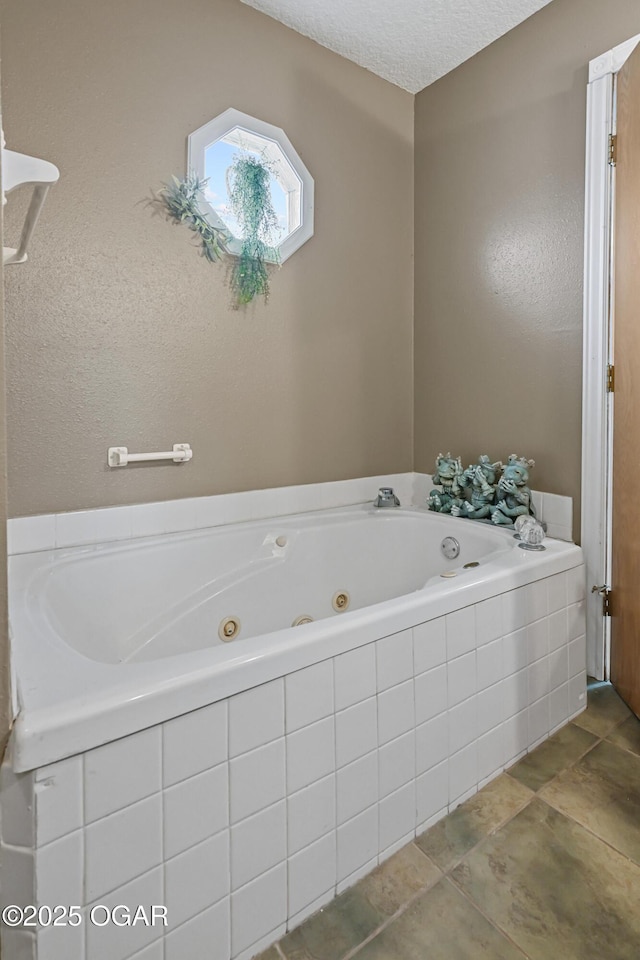 bathroom with tiled bath and a textured ceiling