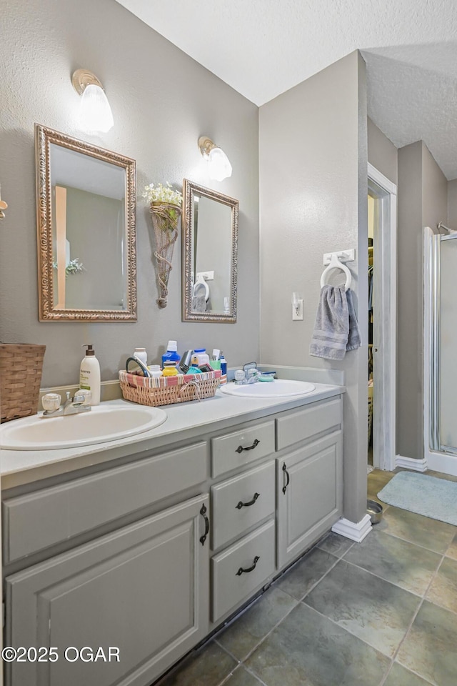 bathroom featuring vanity, tile patterned flooring, a shower with door, and a textured ceiling