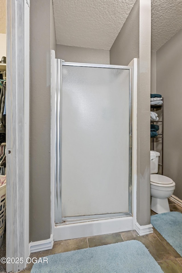 bathroom with toilet, a textured ceiling, and walk in shower