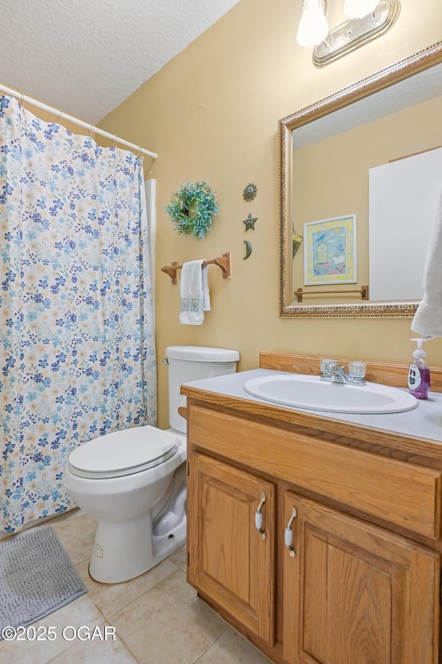 bathroom featuring tile patterned flooring, vanity, a textured ceiling, and toilet