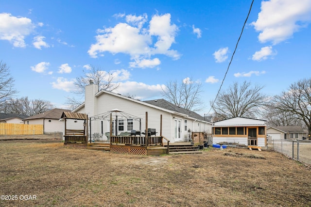 rear view of property with a gazebo, a sunroom, a wooden deck, and a lawn